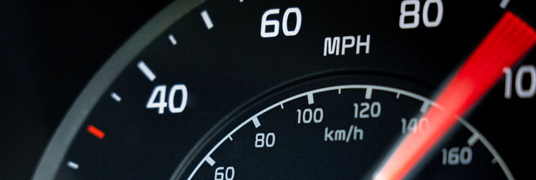 Close-up showing the needle on a car's speedometer moving towards 100 miles per hour.